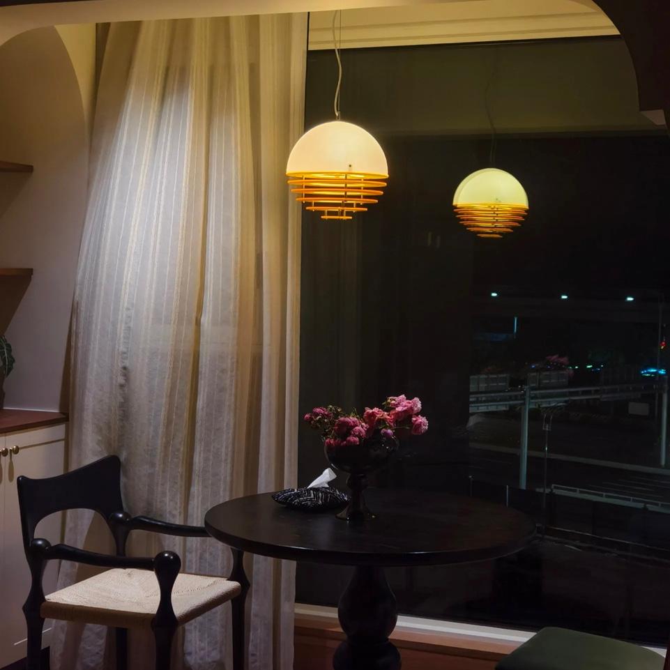 Sunset pendant lamp glowing above a table near a window