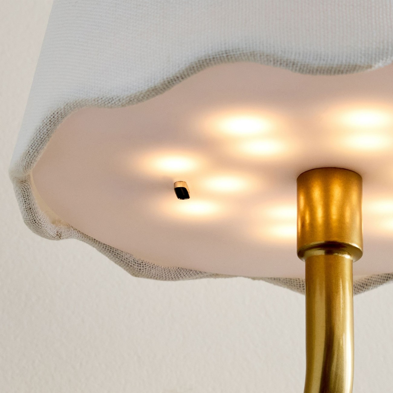 Illuminated scalloped linen shade edge and gold stem connection detail