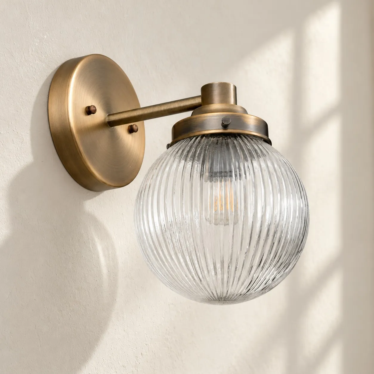 Glorica detail showing the aged brass wall mount, curved arm, socket and ribbed glass shade