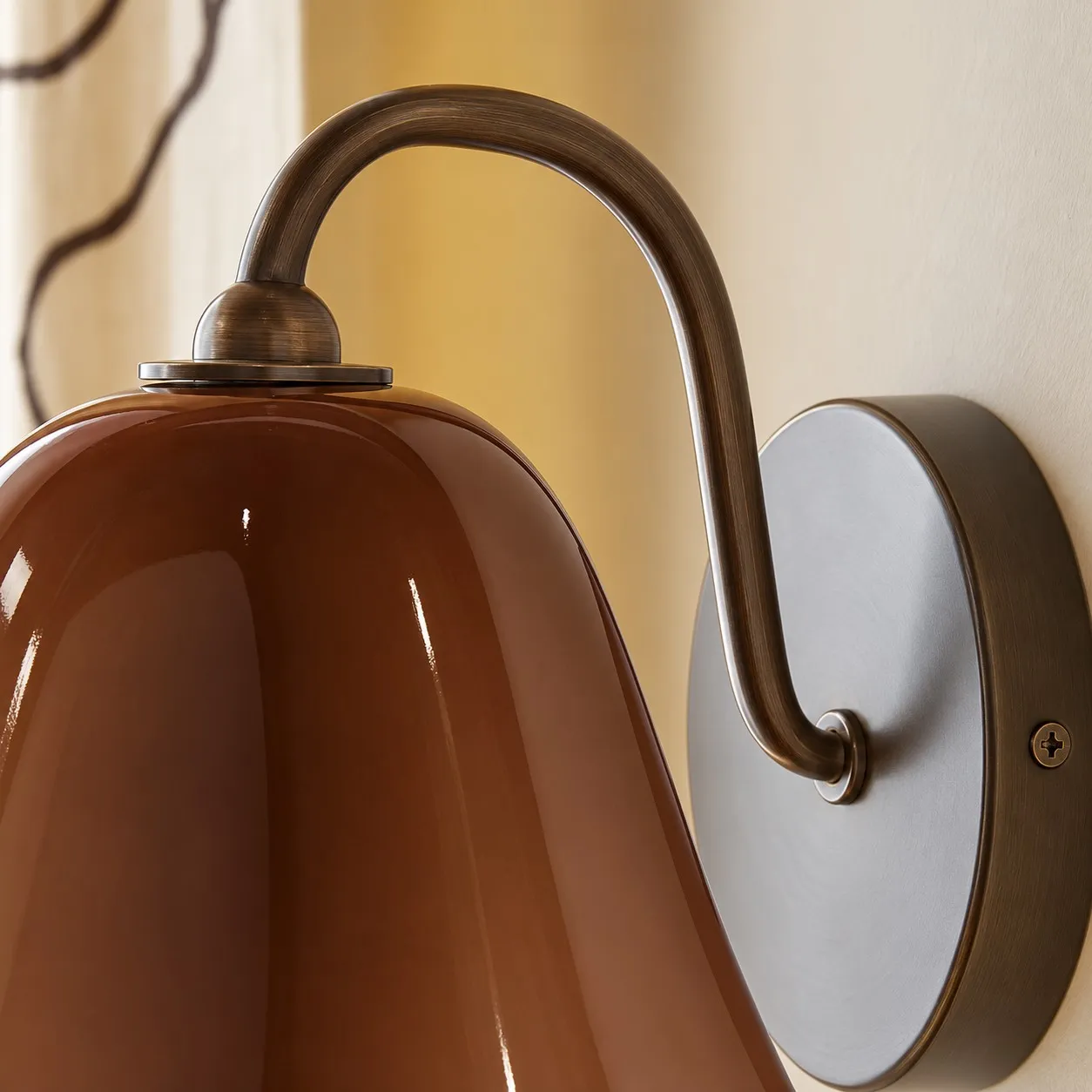 Close-up of the Aged Brass-finished curved arm and circular backplate