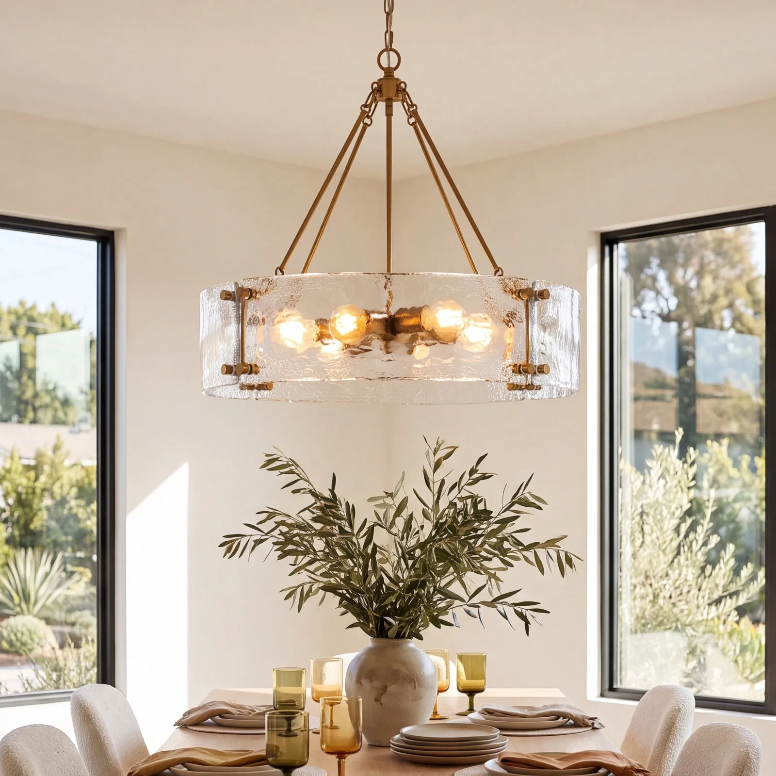 Clear Nicola glass drum chandelier lit above a living room sofa